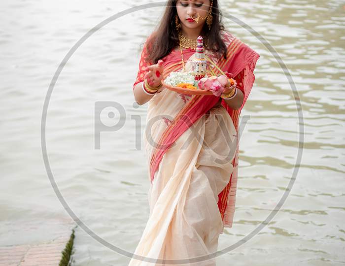 Portrait Of Beautiful Indian Girl Wearing Traditional Indian Saree, Gold Jewellery And Bangles Holding Plate Of Religious Offering In Kolkata, India On September 2020