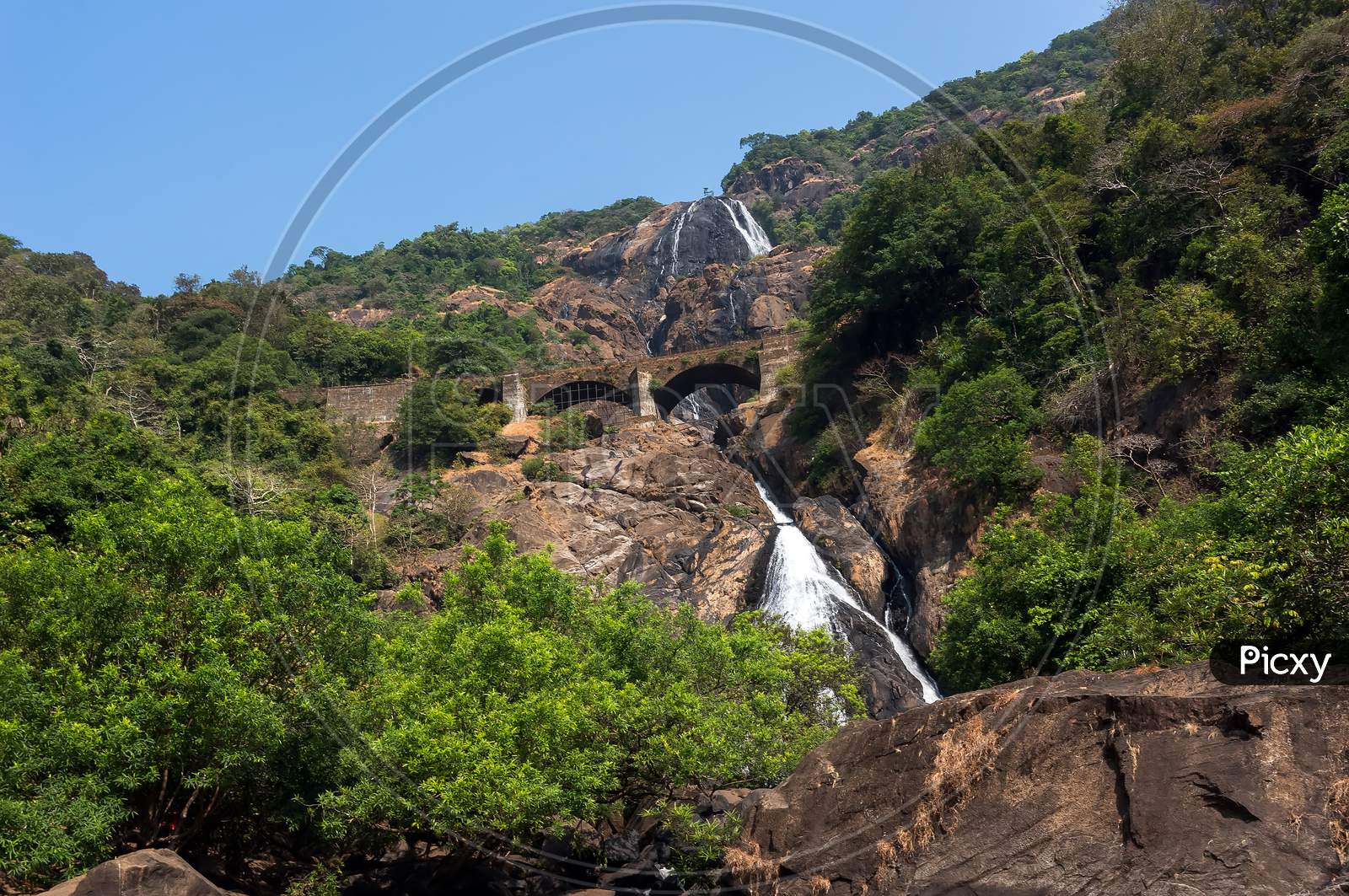 Waterfall In The Mountains Among The Green Trees In The Jungle. Goa