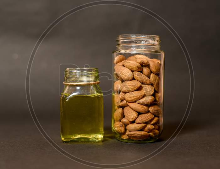 Top view of almonds on dark stone table with wood spoon or scoop. Almond in wooden bowl. Nuts freely laid on dark board. almond oil