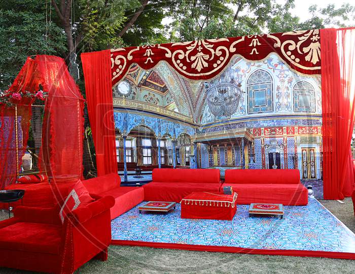 Beautifully Decorated Red Sofas Or Couch Ready For The Guests Sitting At A Engagement Ceremony Venue In Backyard, Wedding Event Decor Concept