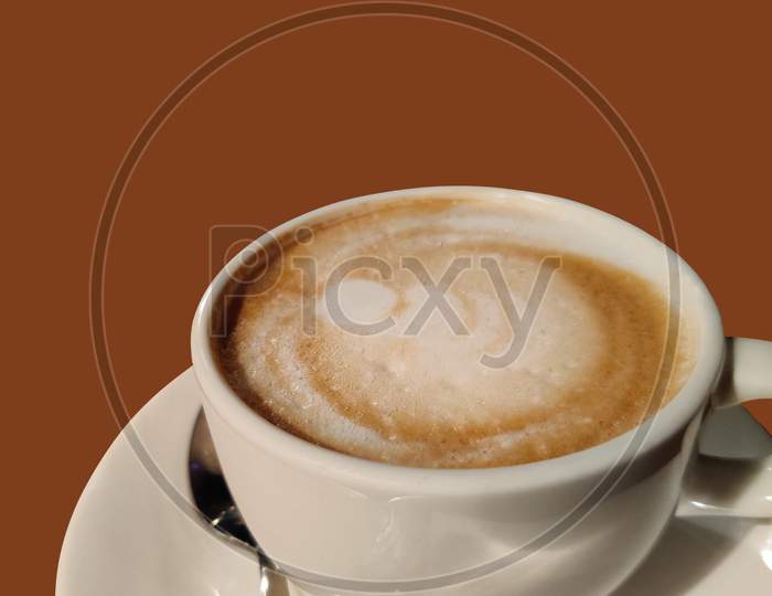 A Cup Of Coffee With Brown Background.