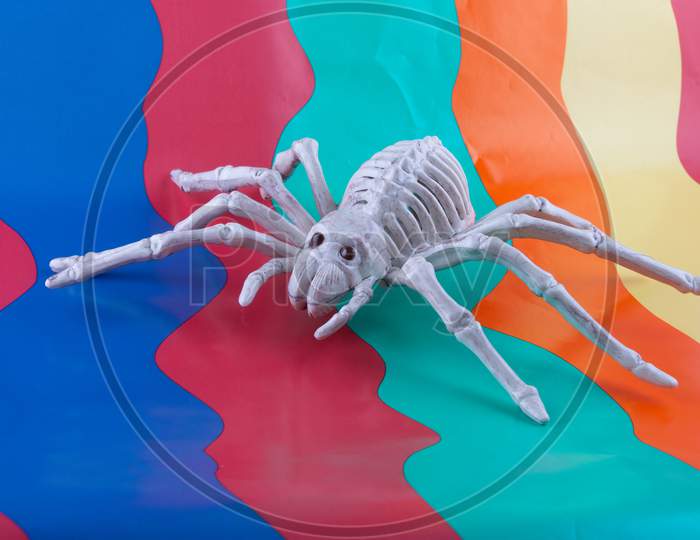 Sinister Spider Skeleton With Red Eyes On Bright Wavy Brightly Coloured Background
