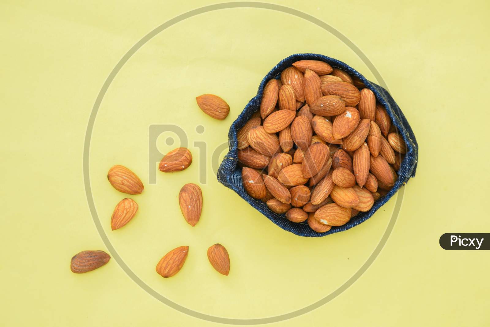 Top view of almonds on dark stone table with wood spoon or scoop. Almond in wooden bowl. Nuts freely laid on dark board. almond oil