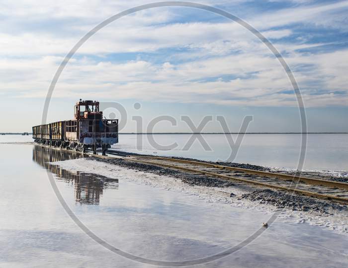 Train Travels From Water. Mined Salt In Lake Burlin. Altai. Russia. Bursolith. Old Train Rides On The Railway Laid In The Water Through The Salt Lake.
