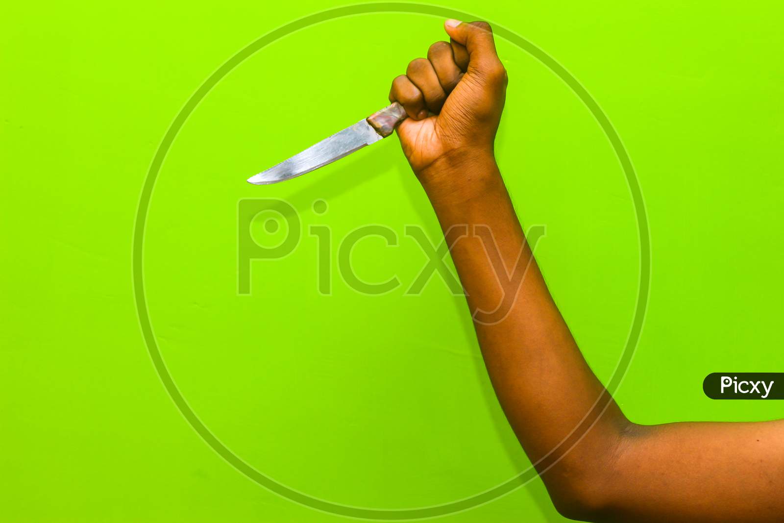 The Human Hand Holding The Knife Isolation On Green Background. Attempting Murder To Using Kitchen Knife.