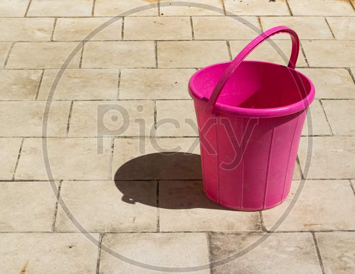 Pink Bucket Placed On A White Terracotta Floor