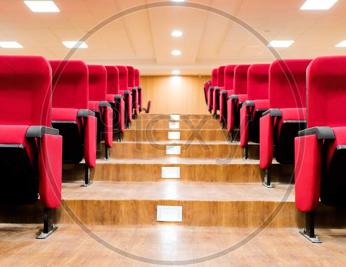 Stairscase Gallery Between Empty Rows Of Seats Of An Auditorium With Red Reclining Rows Of Seats And False Ceiling Led Lights