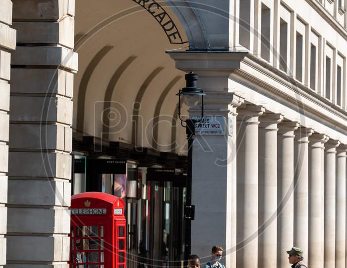 People Wearing Face Masks Walking Past An Icon Red British Telephone Box At Covent Garden During Covid 19 Pandemic