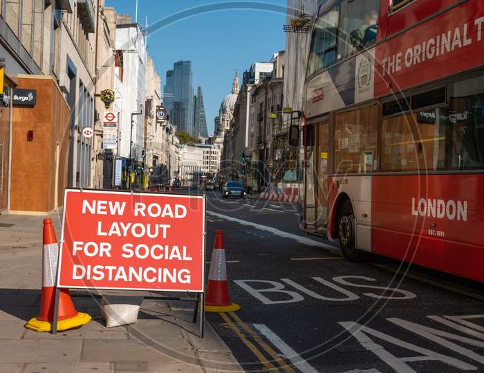 Social Distancing New Road Layouts Sign With A London Double Decker Bus Passing And St Paul'S Cathedral In The Background During Covid 19 Pandemic