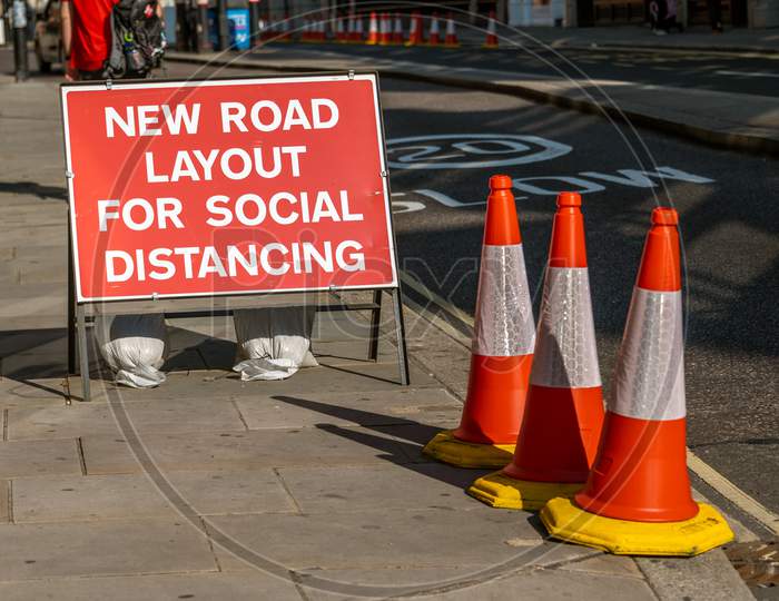 A Uk Road Sign With Orange Traffic Cones Telling Users That The Layout Has Changed To Allow For Social Distancing During Covid 19 Pandemic