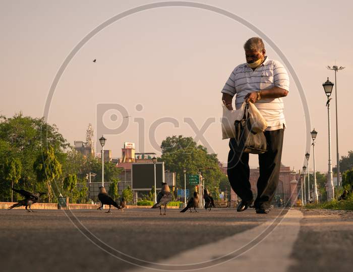 A man feeding birds while walking in the morning