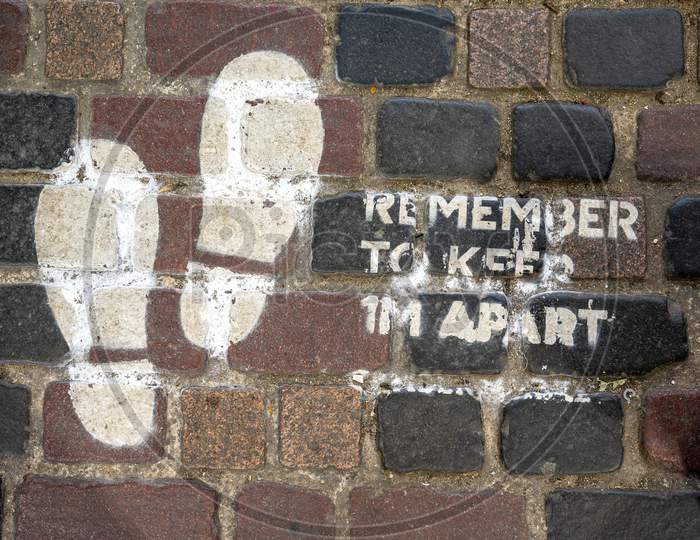 Social Distancing Sign Painted On Old Brick Floor At Camden Market During Covid 19 Pandemic