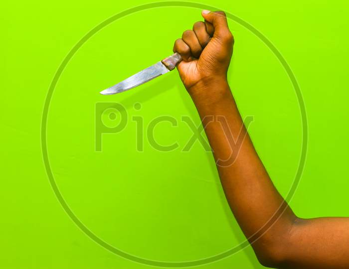 The Human Hand Holding The Knife Isolation On Green Background. Attempting Murder To Using Kitchen Knife.