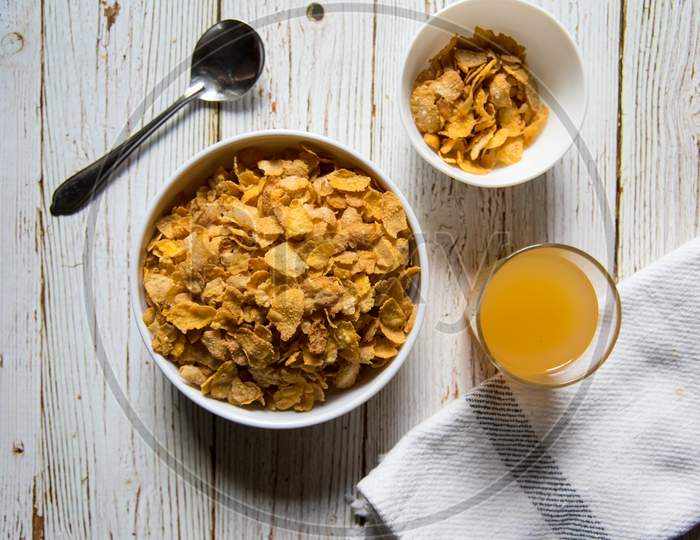 Top view of a bowl of cereal corn flakes and fruit juice