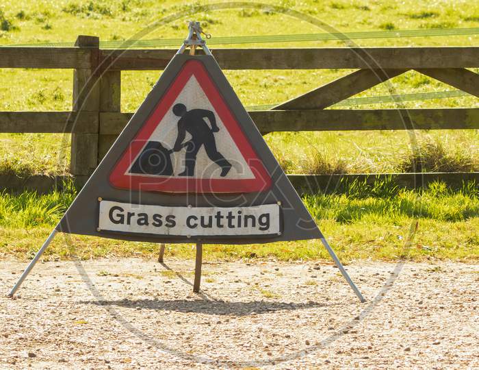 Triangle Warning Sign With Warning Saying Grass Cutting With Copy Space