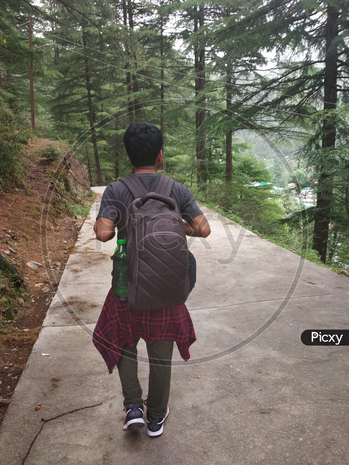 Hiker with backpack hacking on Himalayas mountain roads of India Himalayas mountains Dharamshala Triund Himachal Pradesh
