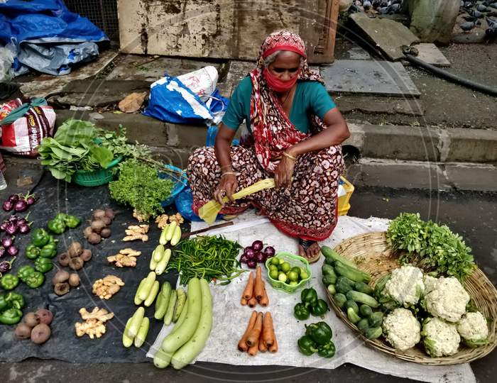 Female vendor selling vegetables on street during COVID-19 outbreak