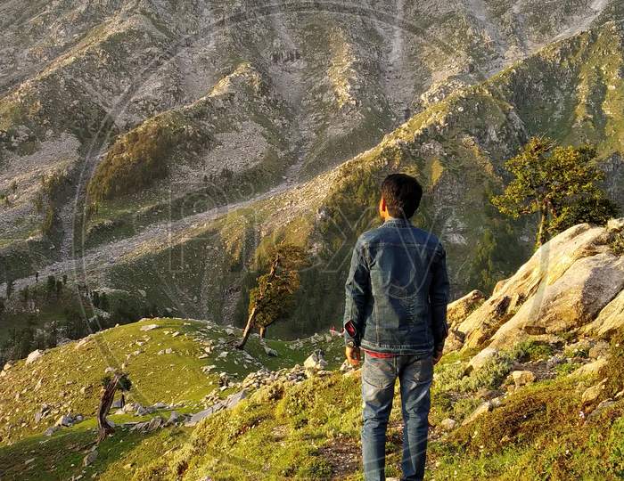 Hiker standing on top of a mountain and enjoying the view in India Mountains Himalayas Dharamshala Triund Himachal Pradesh. Mountaineering sport
