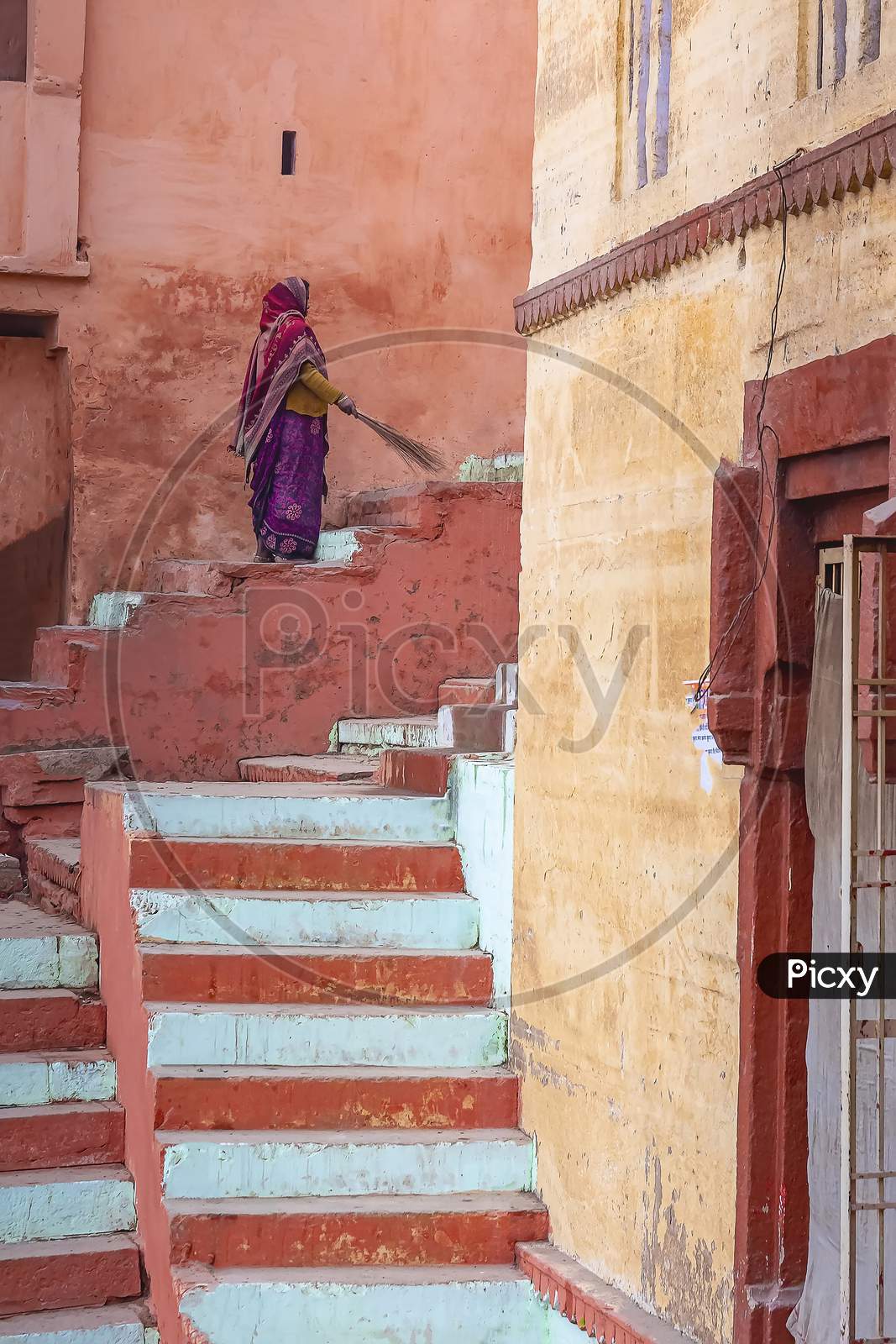 A Cleaning lady sweeps the street in front of her house in Varanasi