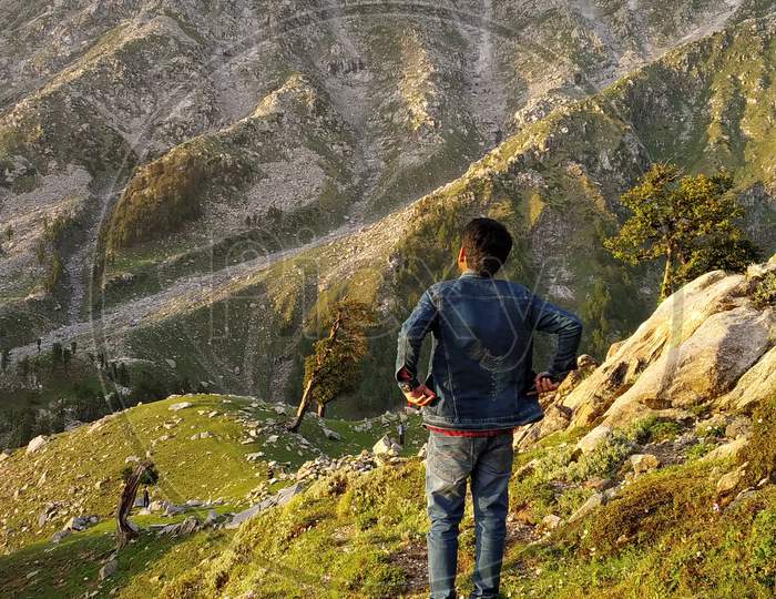 Hiker standing on top of a mountain and enjoying the view in India Mountains Himalayas Dharamshala Triund Himachal Pradesh. Mountaineering sport