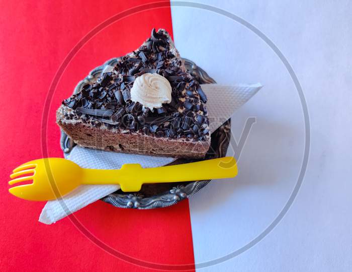 One Black Forest Cake With Yellow Spoon Isolated On Red Background.