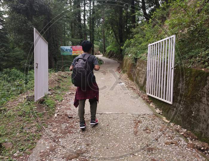 Hiker with backpack hacking on Himalayas mountain roads of India Himalayas mountains Dharamshala Triund Himachal Pradesh