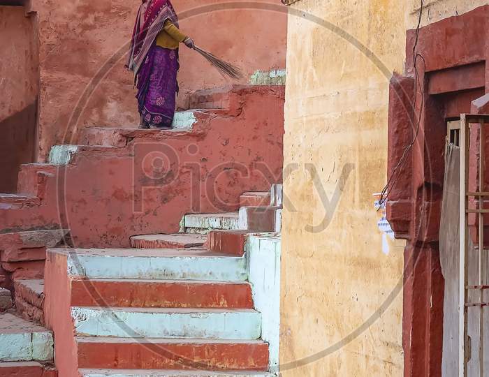 A Cleaning lady sweeps the street in front of her house in Varanasi