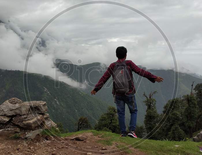 hiker celebrating success on top of a mountain and enjoying the view in India Mountains Himalayas Dharamshala Triund Himachal Pradesh