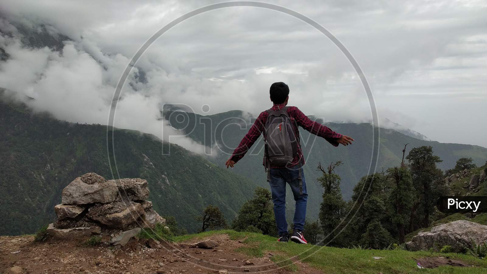 hiker celebrating success on top of a mountain and enjoying the view in India Mountains Himalayas Dharamshala Triund Himachal Pradesh