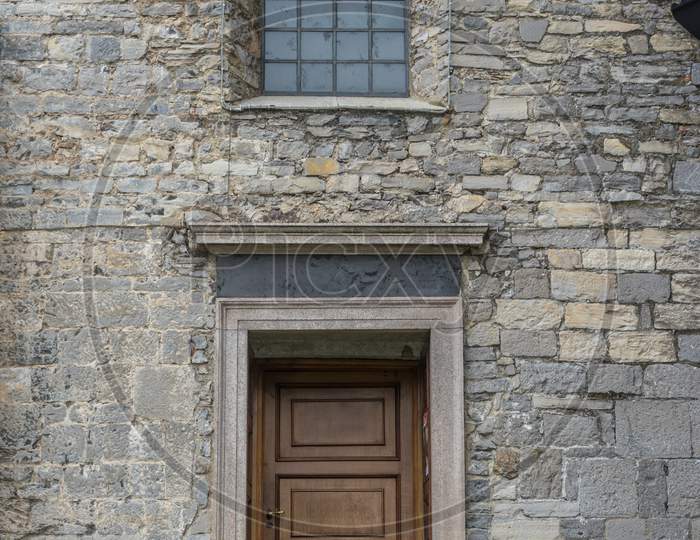 Italy, Varenna, Lake Como, A Door Is Open In Front Of A Brick Building