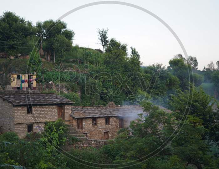 Landscape Of A Village Covered With Green Trees Captured In The Evening.