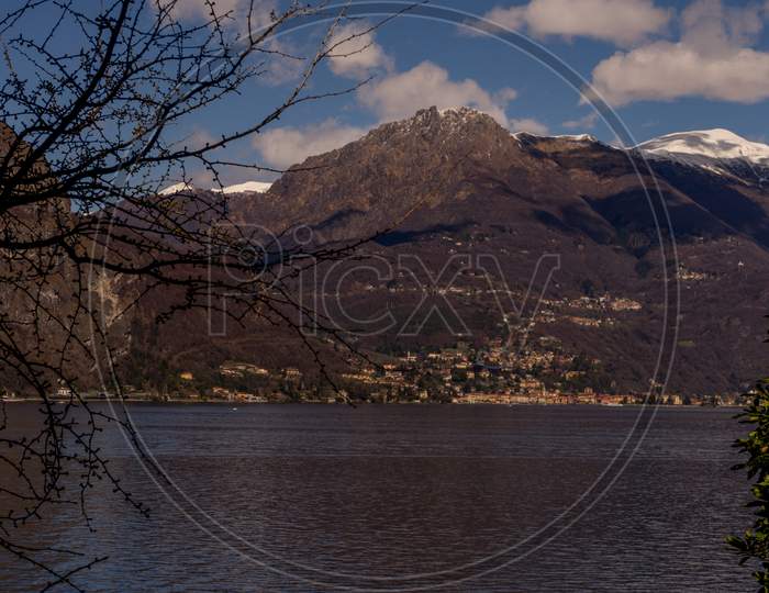 Italy, Bellagio, Lake Como, A Lake With A Mountain In The Background