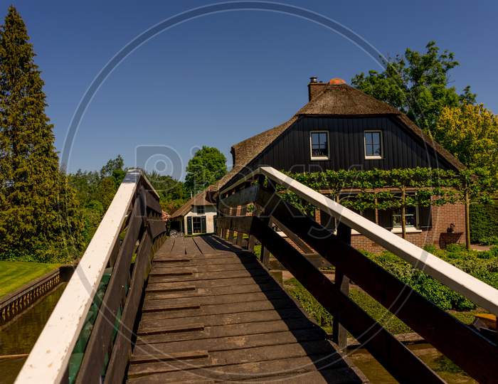 Giethoorn, Netherlands - 26 May: A Bridge Leading Facade Of An Old Cottage House At Giethoorn On 26 May 2017. Giethoorn Is The Venice Of Netherlands
