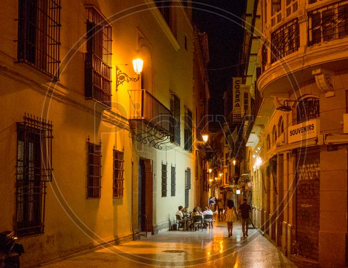 Spain, Malaga - 24 June 2017: Illuminated Street Amidst Buildings At Night