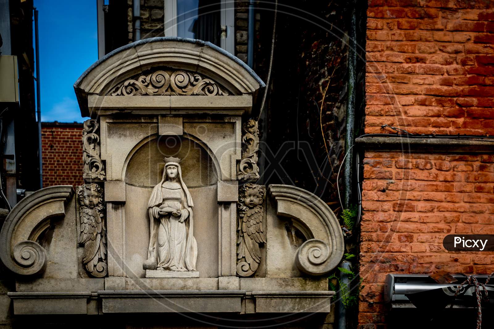 A White Sculpture Of A Madonna On The Gable House In Ghent, Belgium