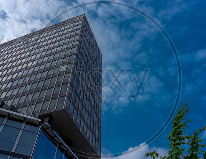 Clouds Fly Across A Blue Sky Over A Glass Windowed Building At Brussels, Belgium, Europe
