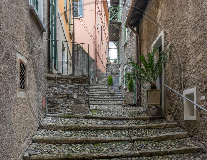 Italy, Varenna, Lake Como, A Stone Building That Has A Sign On A Sidewalk