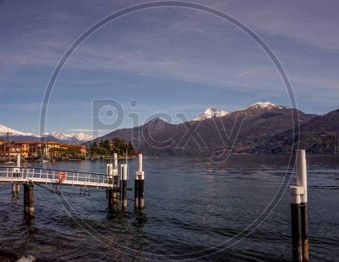 Italy, Menaggio, Lake Como, A View Of A Pier Next To A Body Of Water