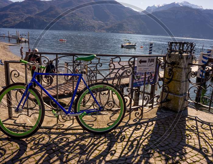 Menaggio, Italy-April 2, 2018: Blue Bicycle Parked At The Waterside Quay, Menaggio, Lombardy