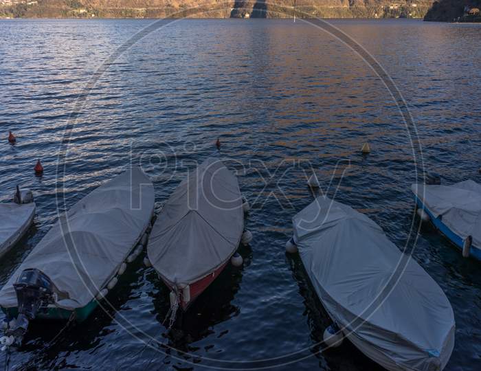 Italy, Lecco, Lake Como, A Boat Is Docked Next To A Body Of Water