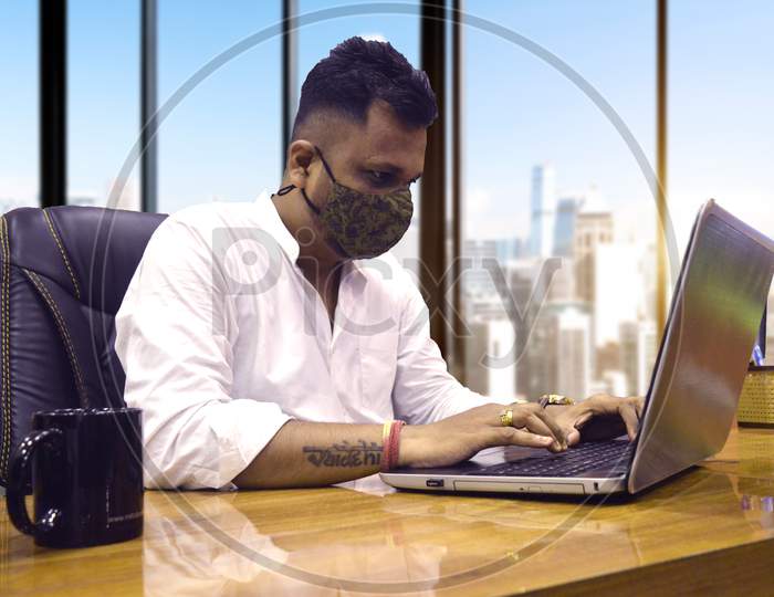 Man working on laptop in office indian with Mask