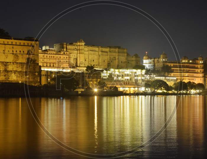 Photograph of famous city palace udaipur with its light reflection on the bank of lake pichola udaipur.