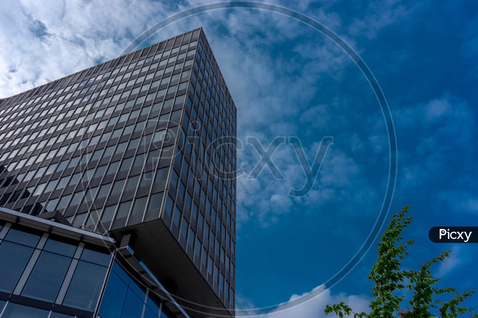 Clouds Fly Across A Blue Sky Over A Glass Windowed Building At Brussels, Belgium, Europe