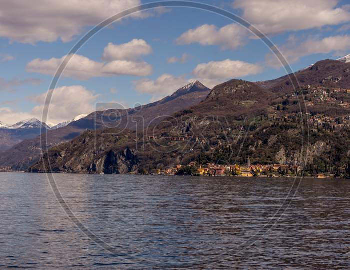 Italy, Bellagio, Lake Como, A Large Body Of Water With A Mountain In The Background