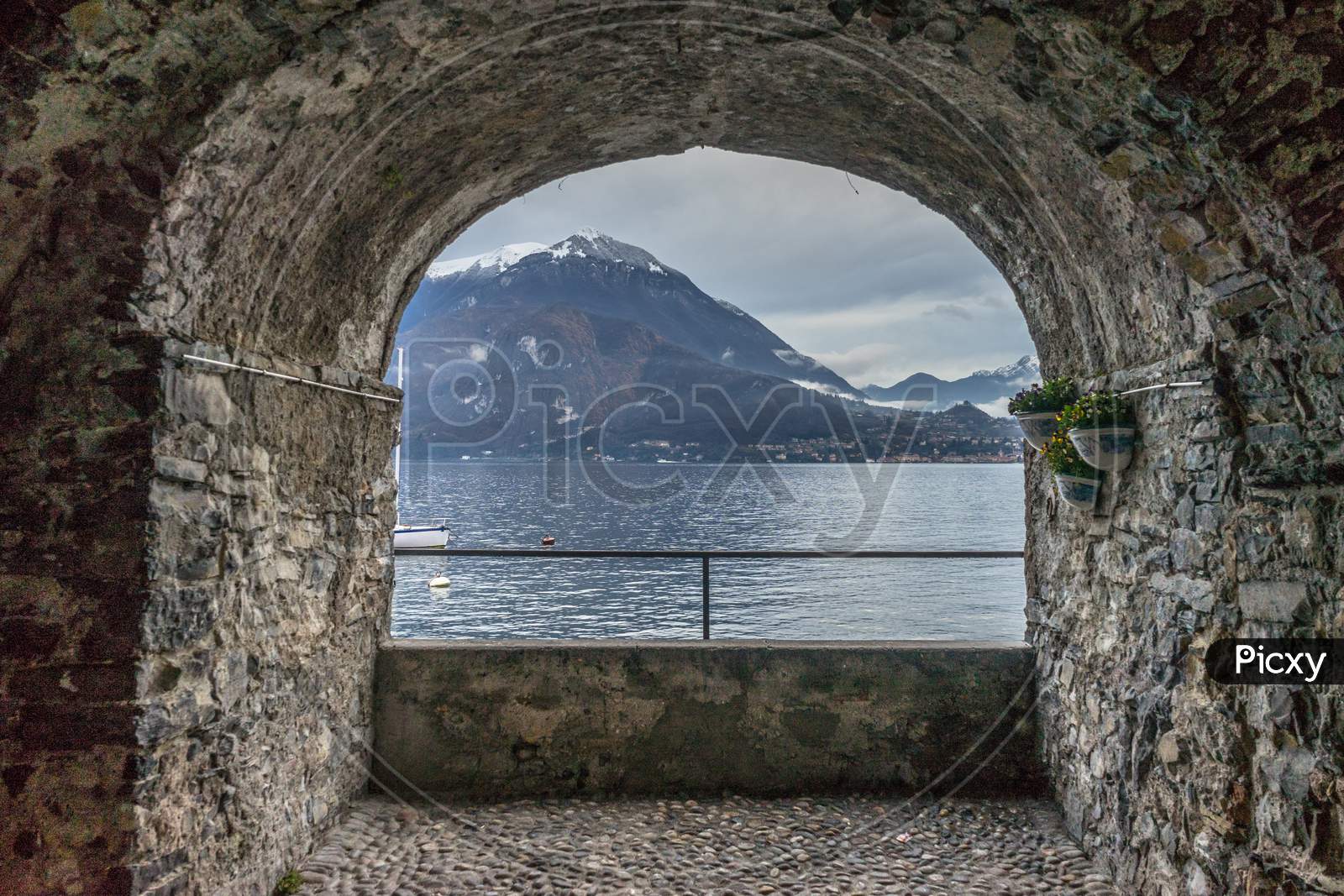 Italy, Varenna, Lake Como, Scenic View Of Sea Against Mountain Seen Through Arch