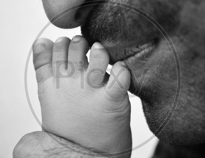 Father Kissing leg of newborn baby.