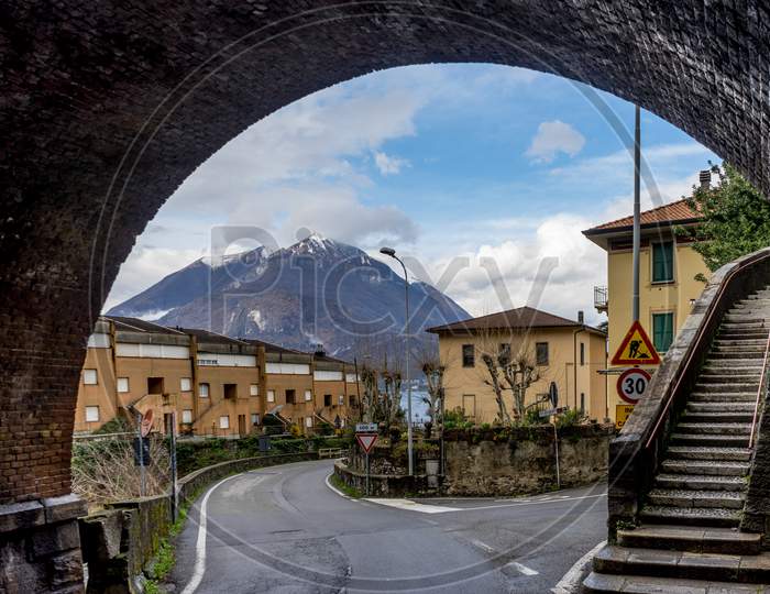 Italy, Varenna, Lake Como, Snow Capped Maountain Viewed Under An Arch