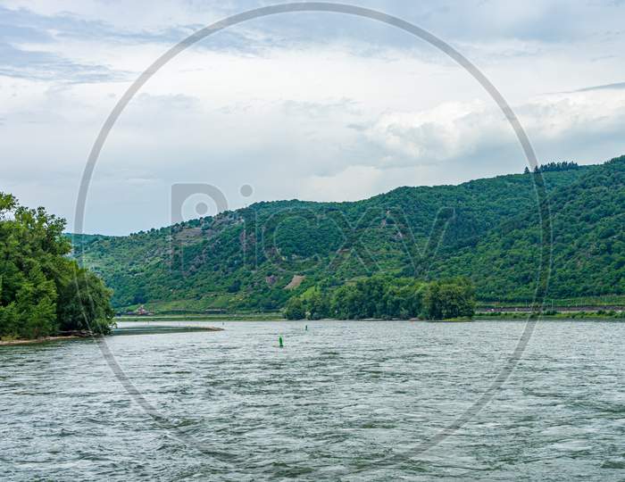 Germany, Rhine Romantic Cruise, A Body Of Water With A Mountain In The Background