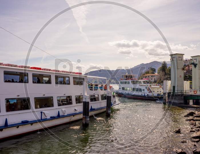 Menaggio, Italy-April 2, 2018: Traffic Jam With Ferry Boat On The Lake Como Transporting People With Mountain In Background