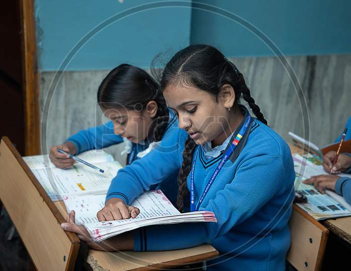 Jodhpur, Rajasthan, India - Jan 10Th 2020: Primary Indian Female Students Studying In The Classroom Taking Exam / Test Writing In Notebooks. Education Concept.